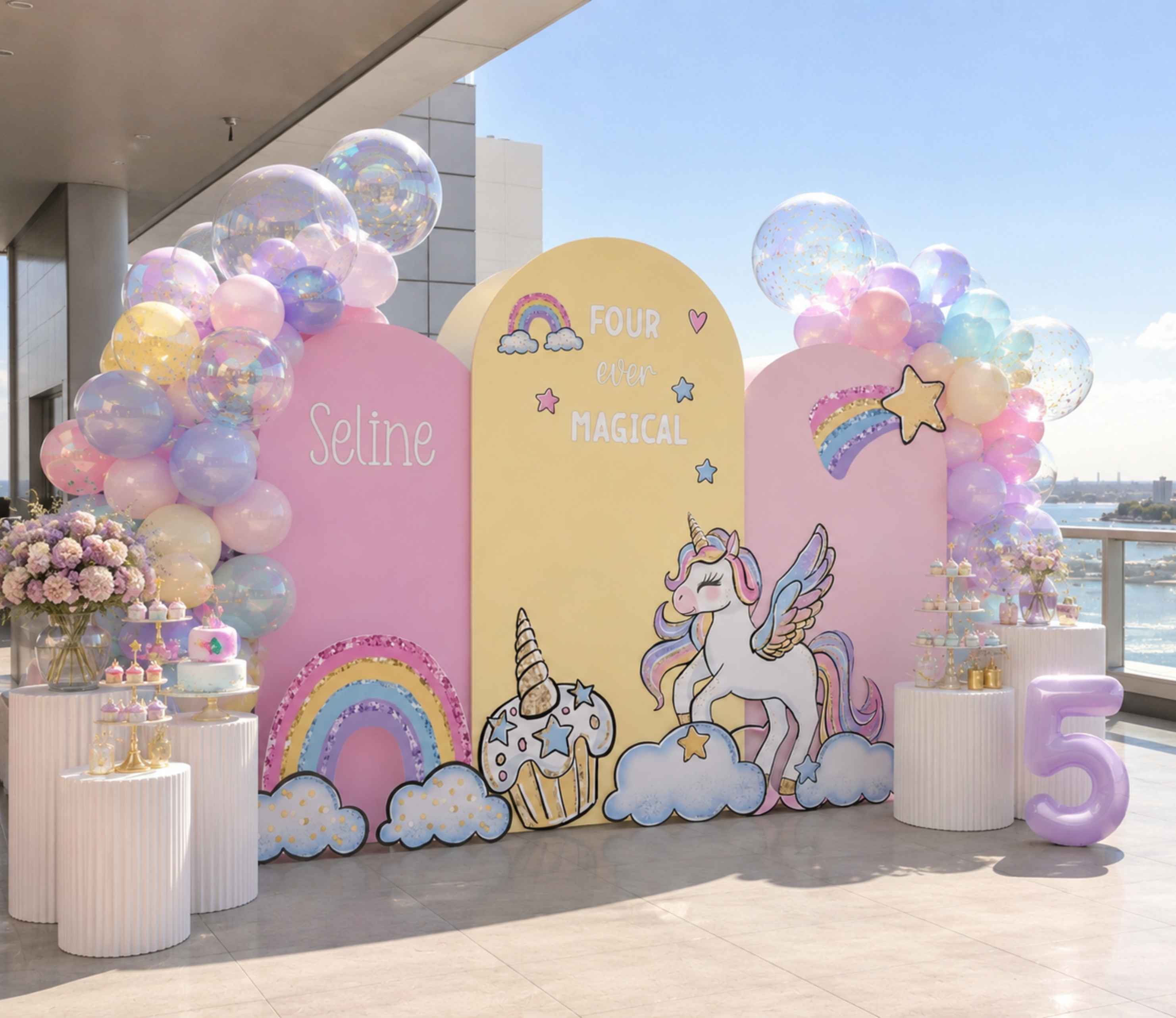 Pastel unicorn party backdrop set with blue pink and yellow panels, rainbow details and matching unicorn birthday cutouts.