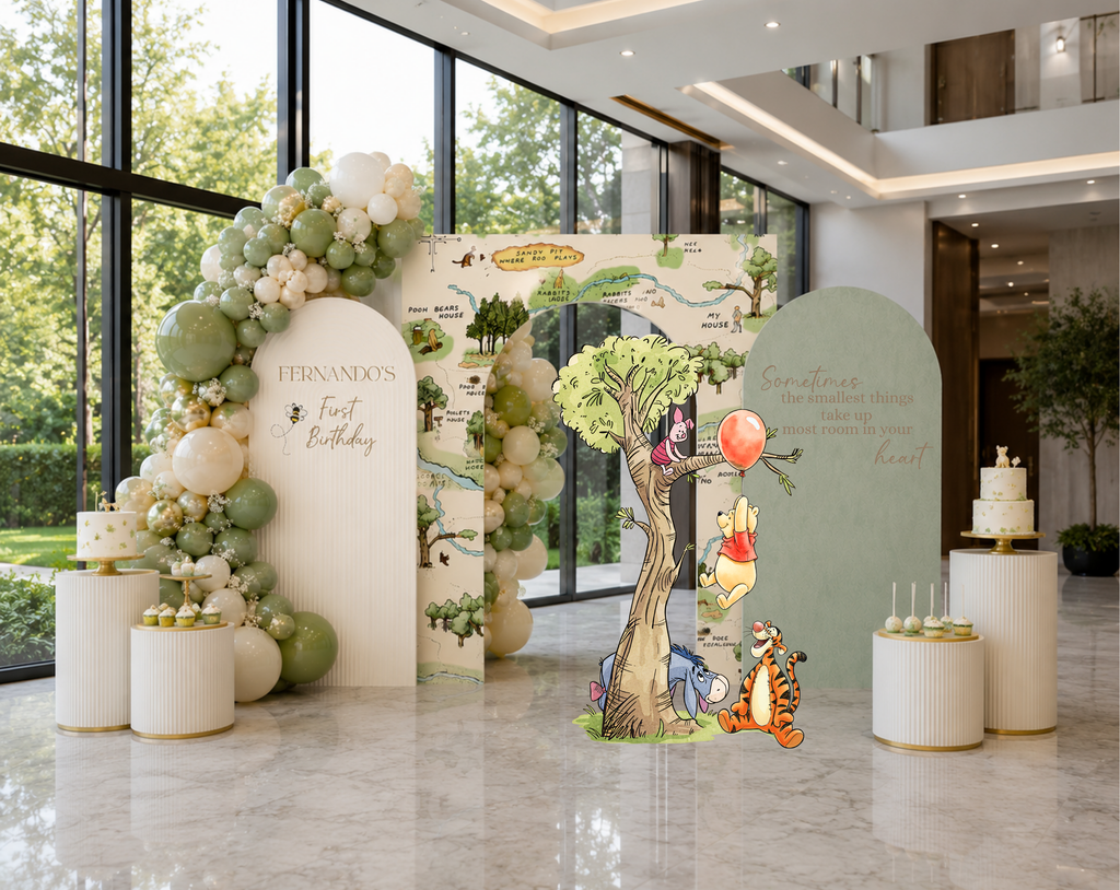 Outdoor woodland baby shower backdrop with sage and ivory panels, greenery and classic bear inspired character decorations.