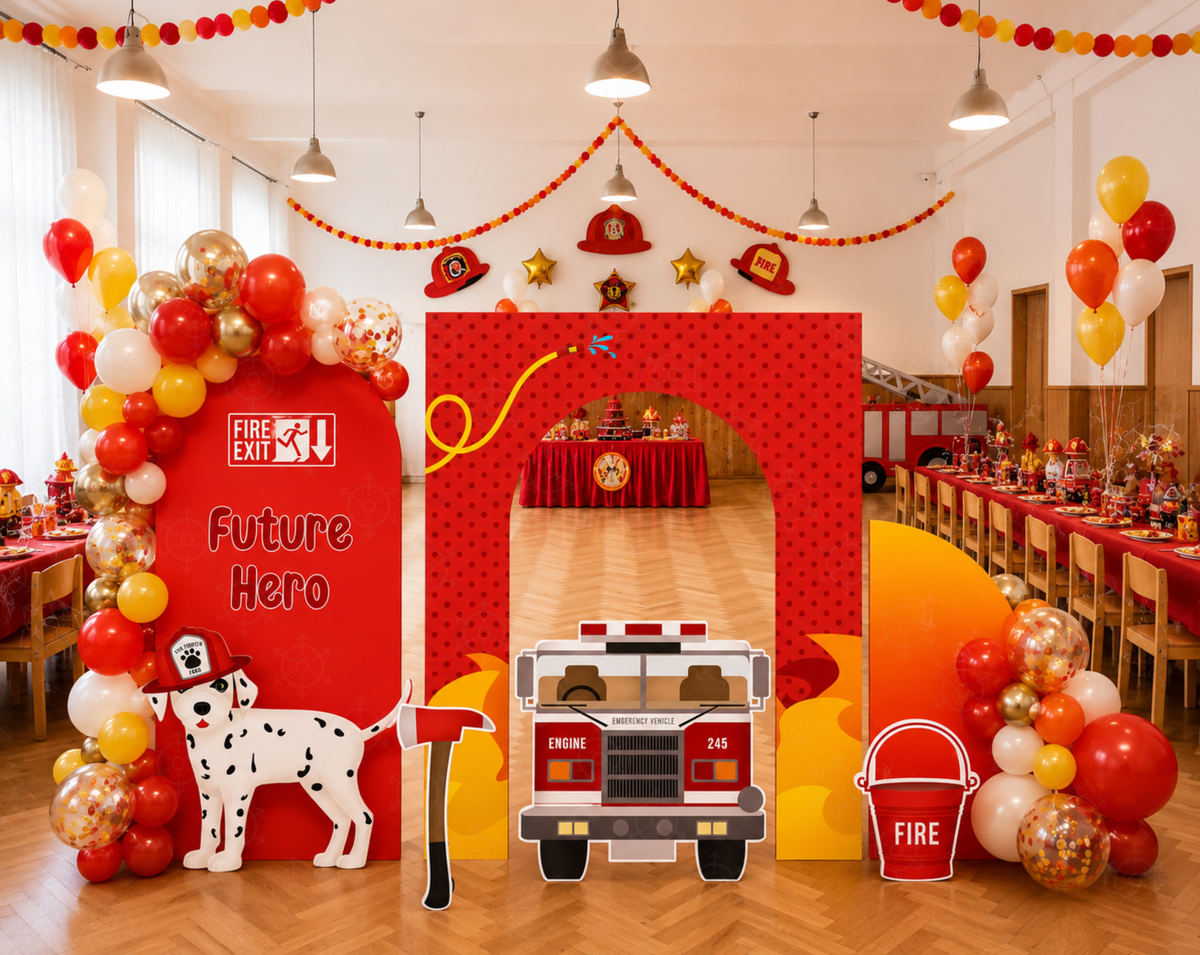 Outdoor firefighter birthday setup with a green hedge wall, red station backdrop, playful cutouts, balloons and kids seating.
