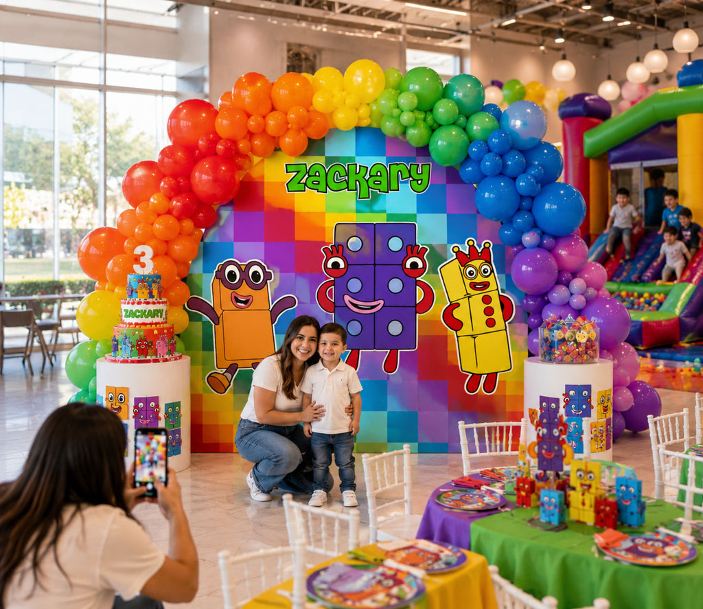 Large Numberblocks birthday party setup with rainbow balloons, colorful backdrop panels and matching character cutouts for kids.
