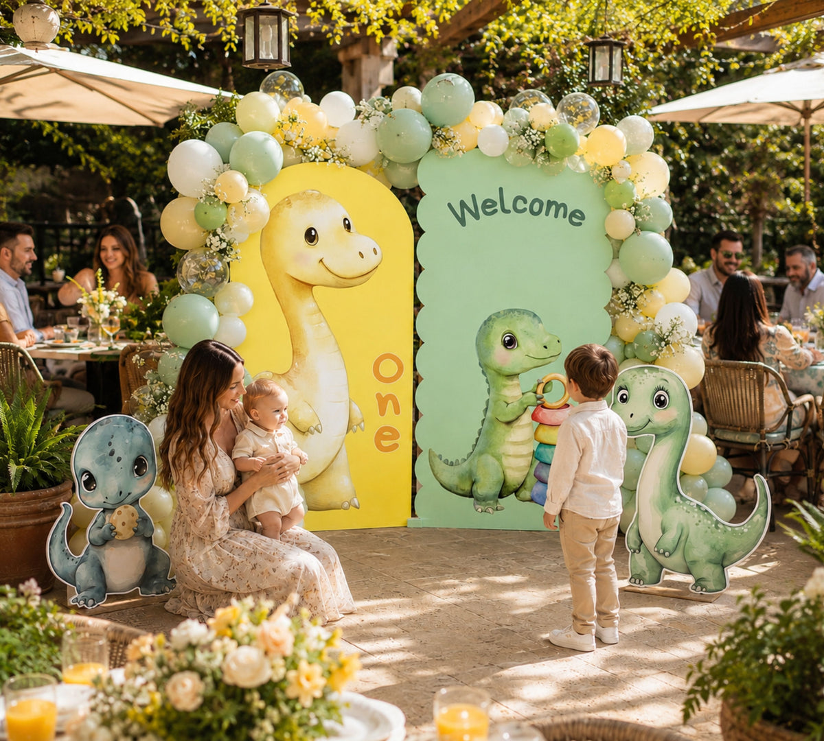 Outdoor baby dinosaur birthday setup with green arch panel, cute dino cutouts and soft pastel balloon decor for a personalized kids party.