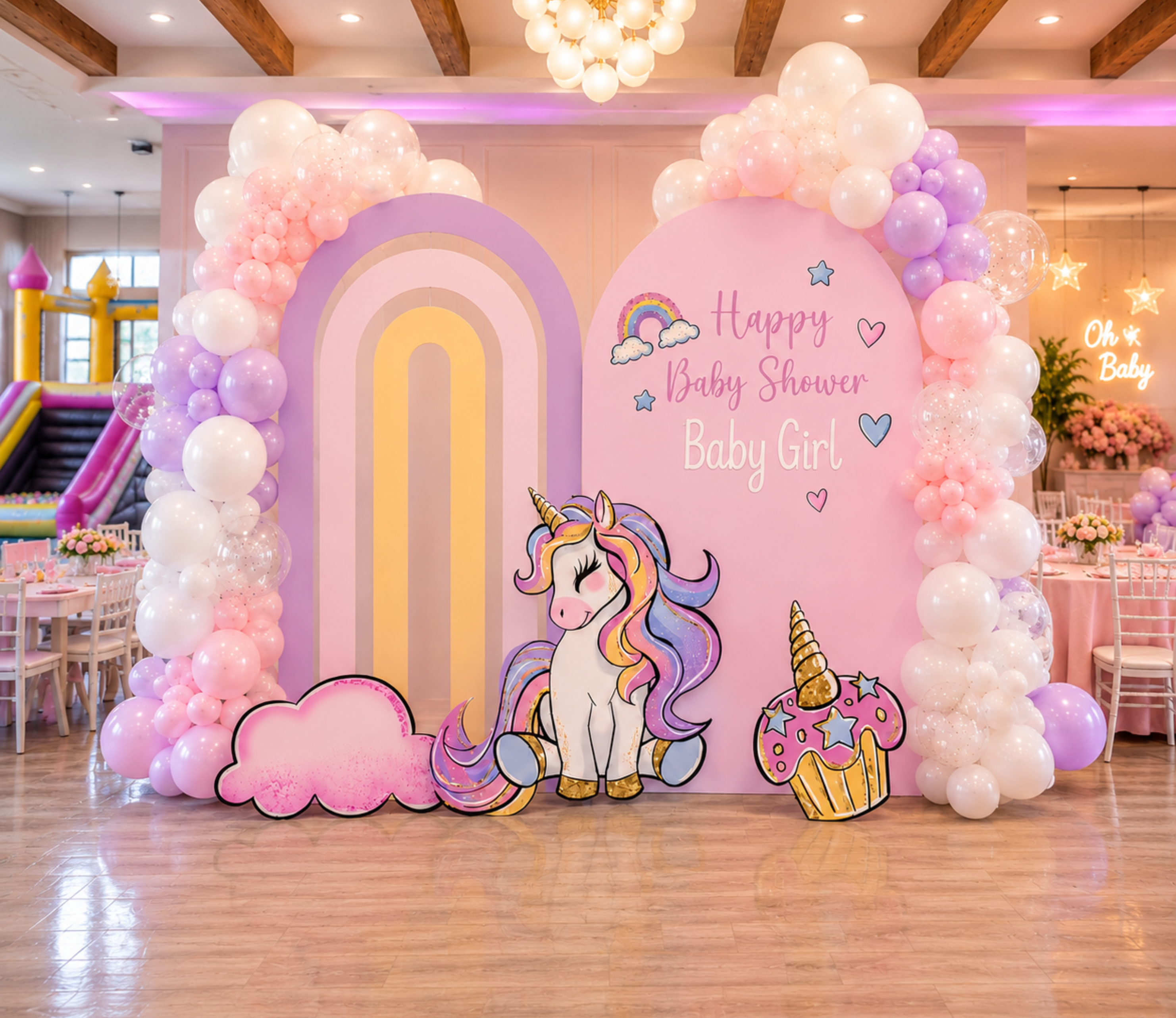 Pink pastel unicorn birthday backdrop with rainbow arch, floral balloon garland and matching unicorn cutouts for an elegant kids party.