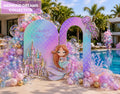 Outdoor mermaid birthday backdrop with pastel rainbow arches, tropical palm details, balloons and under the sea party decorations.