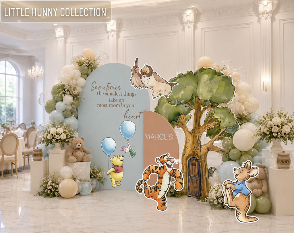 Personalized classic bear baby shower backdrop with woodland tree, pastel blue arch panels, white balloons and storybook character cutouts.