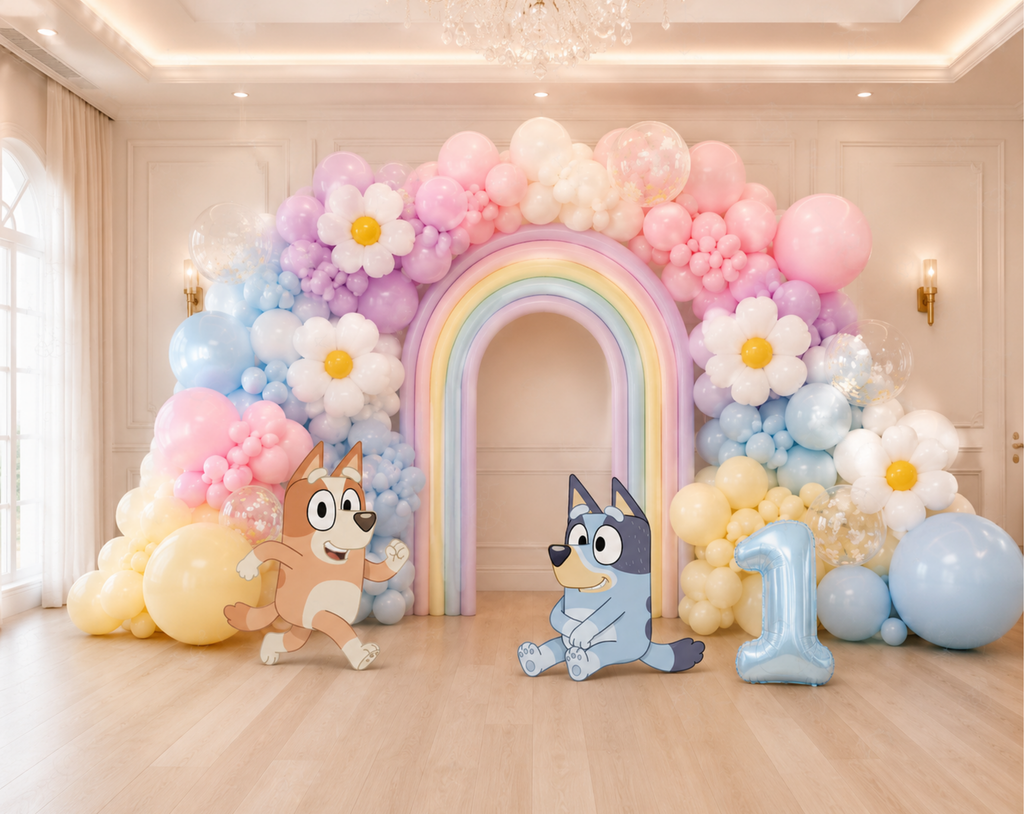 Indoor puppy family birthday backdrop with pastel rainbow arch, blue and pink balloons and personalized character decorations.
