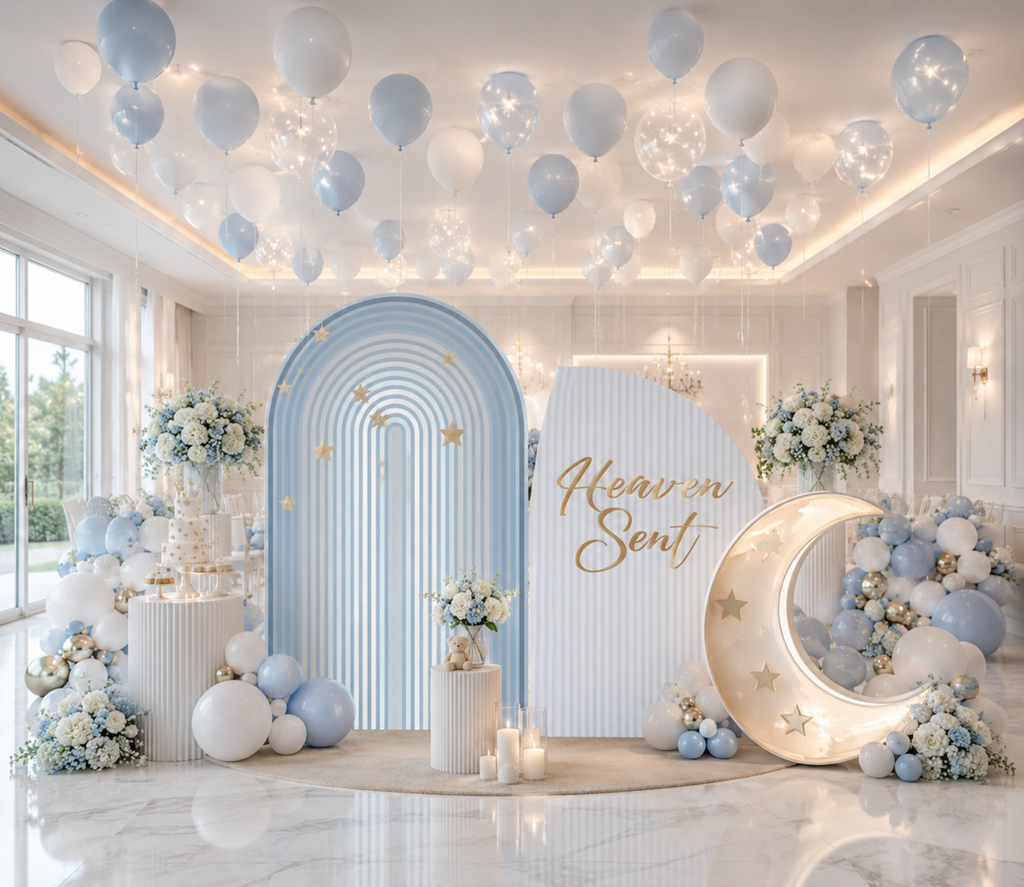Light blue baby shower backdrop with moon and star details, neutral balloon garland and celestial decorations for a baby boy celebration.