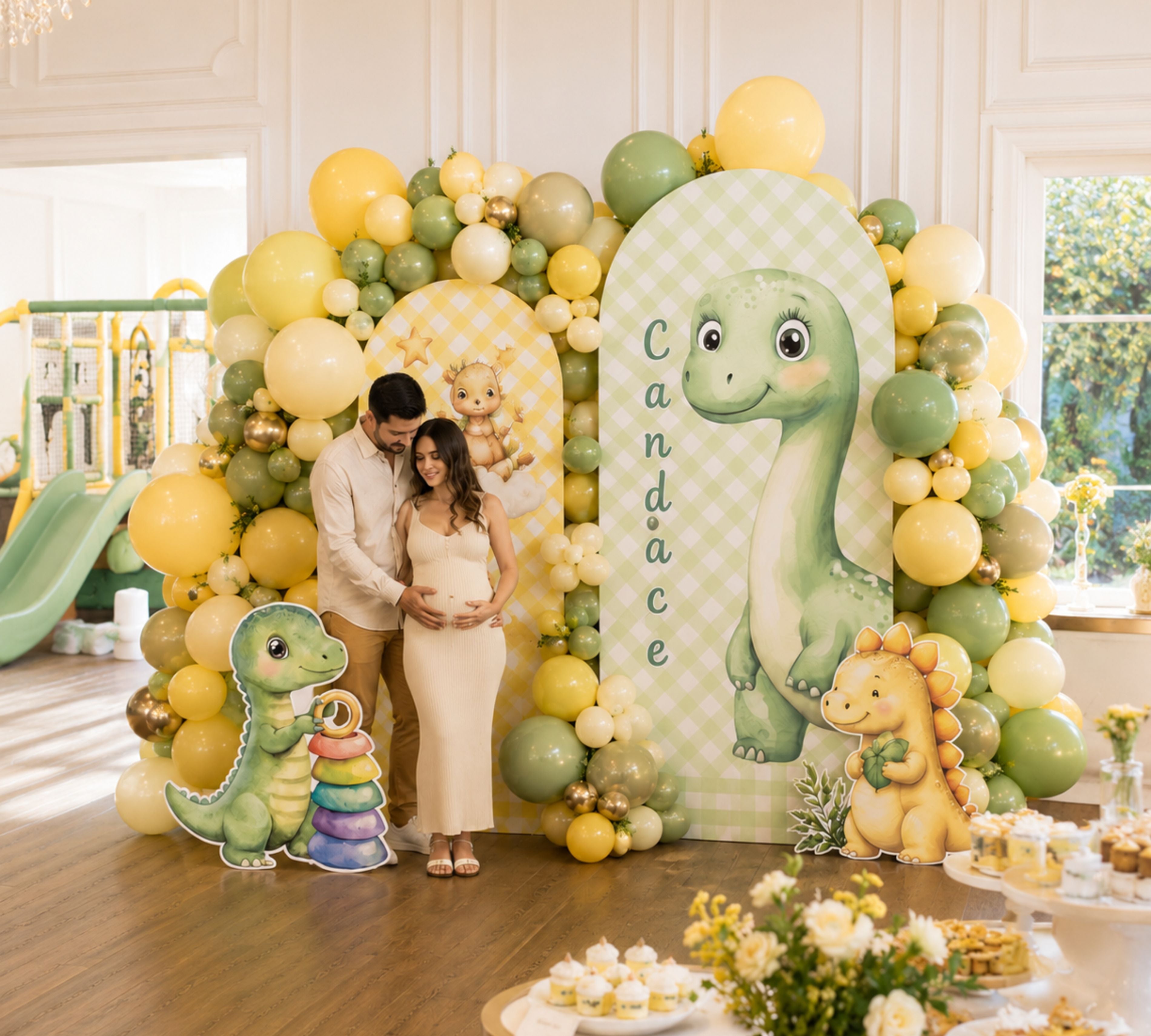 Cute baby dinosaur backdrop with yellow and green balloon garland, baby dino cutouts and soft neutral party decor for a kids celebration.