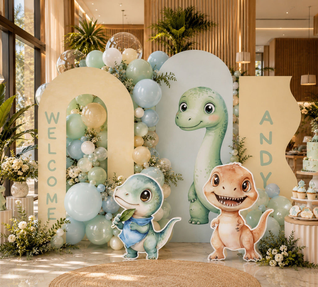 Personalized dinosaur party backdrop with green arch panels, pastel balloon clusters and cute baby dinosaur cutouts for a first birthday setup.