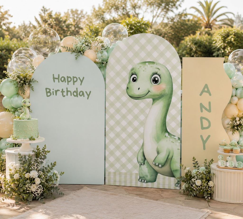 Outdoor baby dinosaur backdrop with sage green arch panels, balloon decor and personalized dino party styling for a baby celebration.
