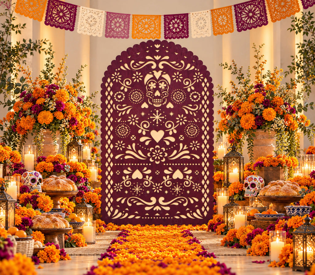 Deep burgundy papel picado-inspired party backdrop with marigold flowers, candles and warm orange fall celebration decorations.
