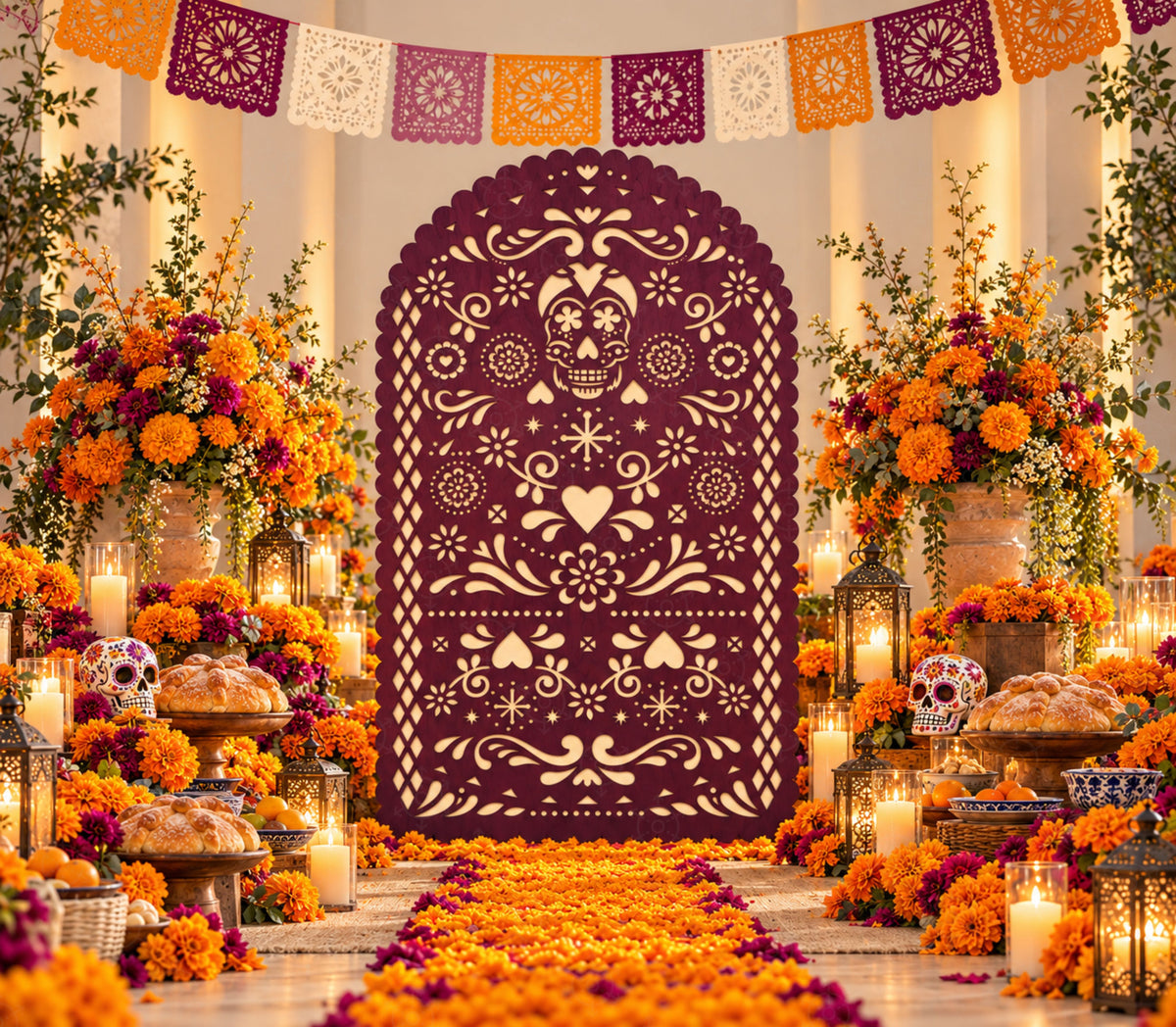 Deep burgundy papel picado-inspired party backdrop with marigold flowers, candles and warm orange fall celebration decorations.
