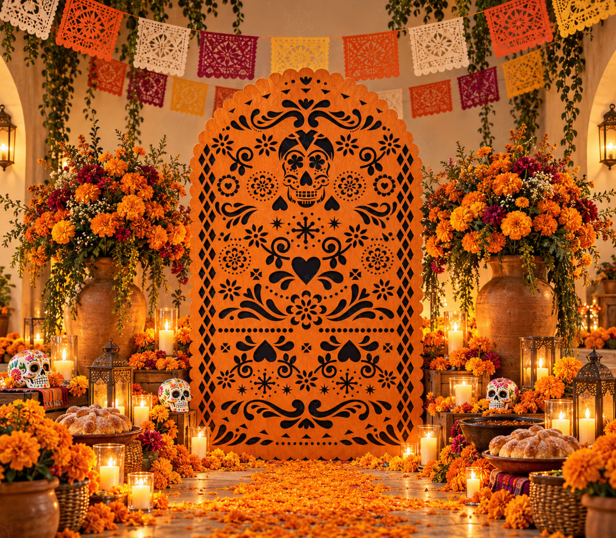 Orange papel picado-inspired party backdrop with marigold florals, candles, festive banners and warm autumn fiesta decorations.