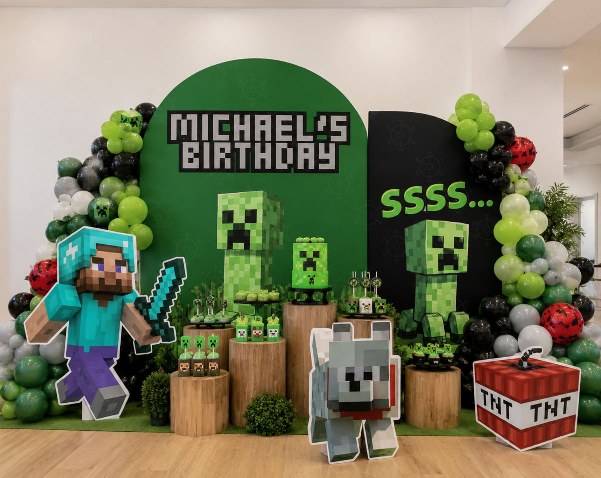 Outdoor pixel game birthday setup with green adventure fort panel, balloon garland, rustic pedestal props and custom gamer party decorations.