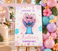 Personalized Hawaiian blue alien birthday welcome sign displayed on an easel with tropical flowers, pastel balloons and colorful island party decor.