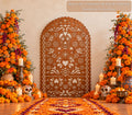Terracotta papel picado-inspired party backdrop surrounded by orange marigold florals, candles and warm Mexican-inspired fall celebration decor.