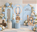 Neutral blue aviator bear birthday backdrop with arched panels, beige balloon garland and matching teddy bear party decor.