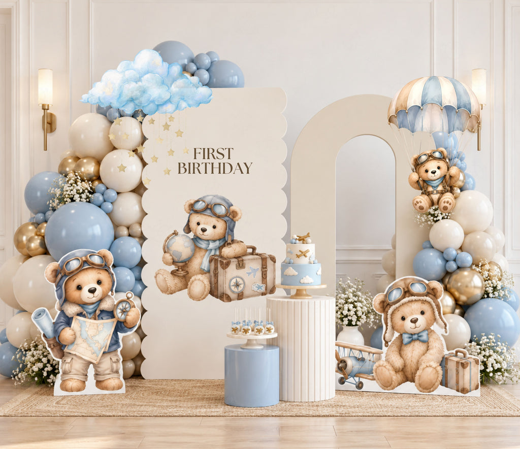 Soft blue aviator bear birthday backdrop with neutral balloons, hot air balloon details and coordinated baby boy party decorations.