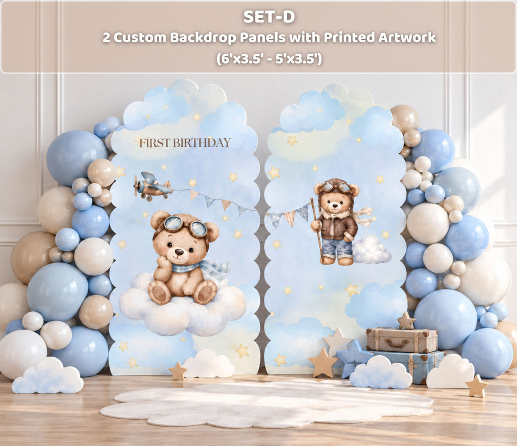 Blue aviator bear first birthday backdrop set with arched panels, neutral balloon accents and matching teddy bear decorations.