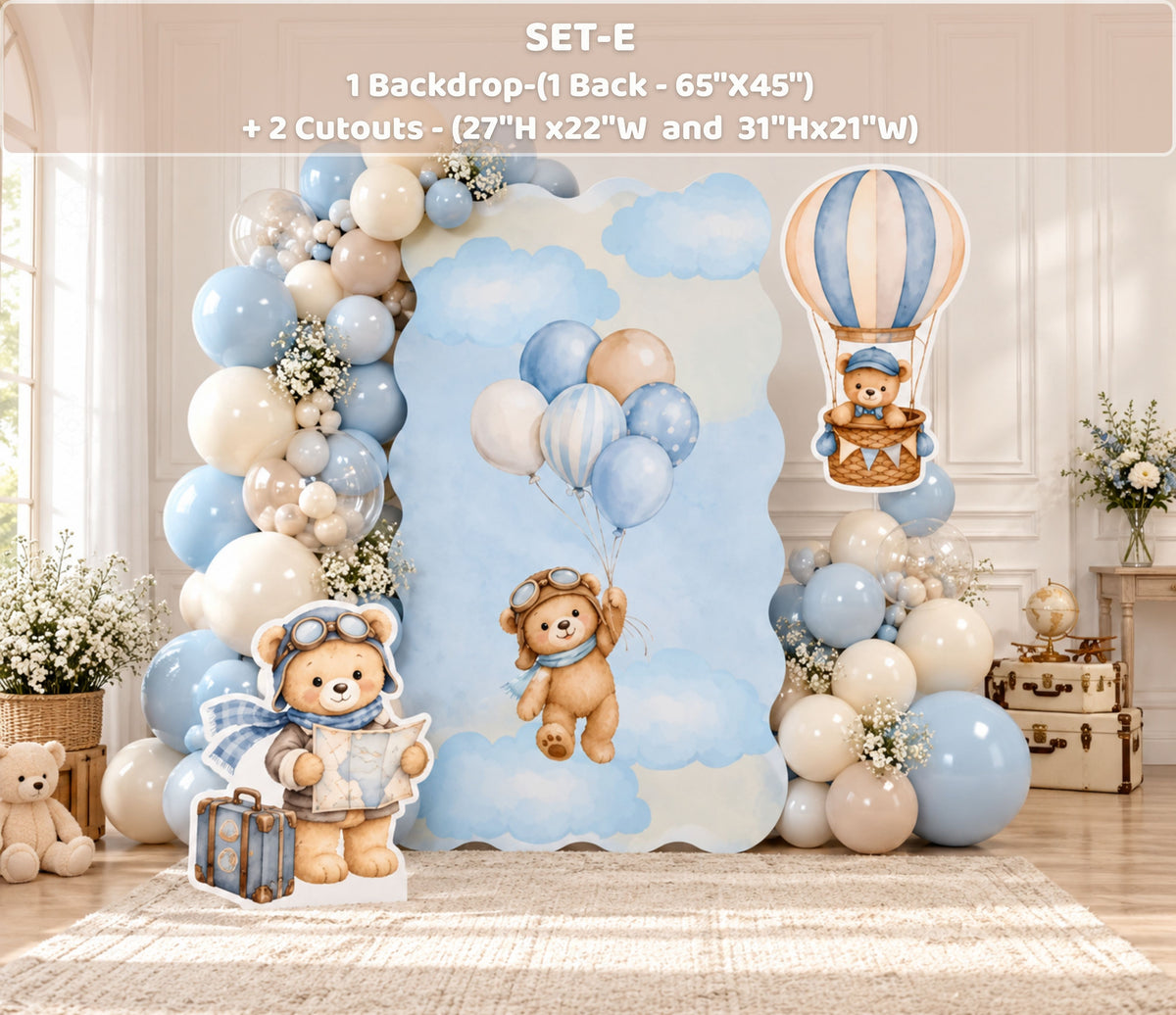 Aviator bear first birthday backdrop with light blue and neutral panels, beige balloon garland and matching bear-inspired party decor.