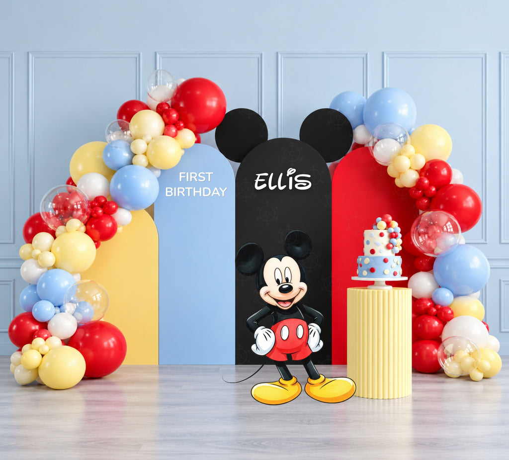 Classic mouse birthday backdrop with blue, yellow and black arch panels, balloon garland and matching party cutouts.