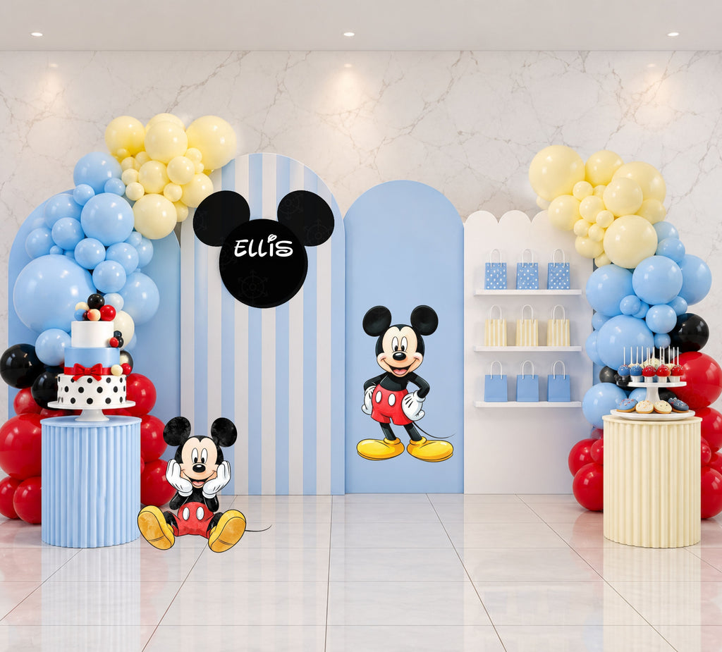 Classic mouse birthday backdrop with light blue and white arch panels, yellow blue and red balloon decor, personalized mouse-head sign and matching character cutouts.