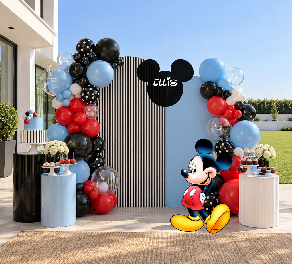 Classic mouse party backdrop with blue and gray arch panels, balloon garland and coordinated birthday decorations.