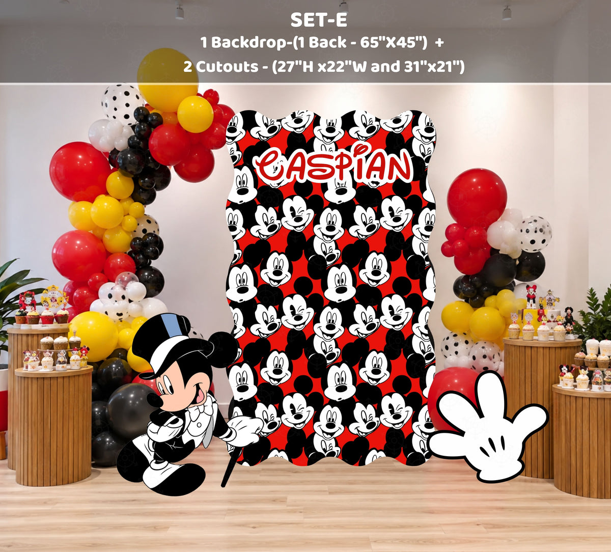 Classic mouse outdoor birthday backdrop with blue panel, red and black balloon garland and themed party decorations.