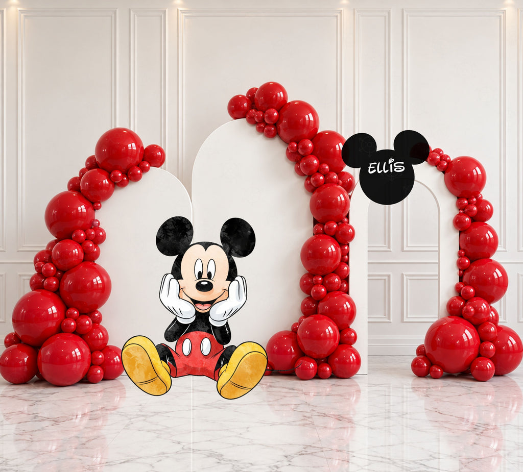 Classic mouse birthday backdrop with three white arched panels framed by red balloon garlands, large character cutout and personalized black mouse-head sign.