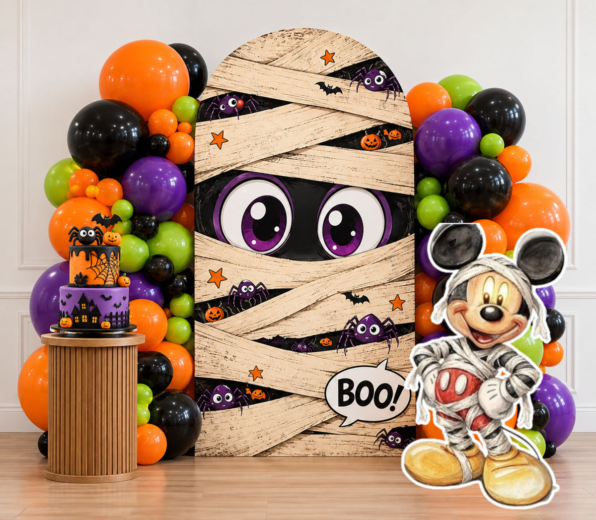 Mummy-inspired spooky birthday backdrop with orange purple green and black balloons, themed cake display and matching character cutout.