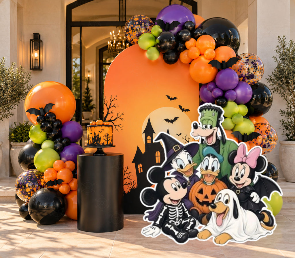 Orange spooky birthday backdrop with haunted house silhouette, black purple and green balloon garland and coordinated character cutouts.
